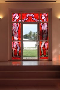 The fifth window — one of the two windows on the upper floor surrounding the exit doors leading to the university campus — shows the (doubled) image of the snake after it had received back its hands, legs, and wings. It now looks like a human covered in reptilian scales. These two figures stand on both sides of the door and hold together a kind of a ribbon that quotes a sentence from ‘Ro’achem’: “And you shall be like leeches to knowledge.” 