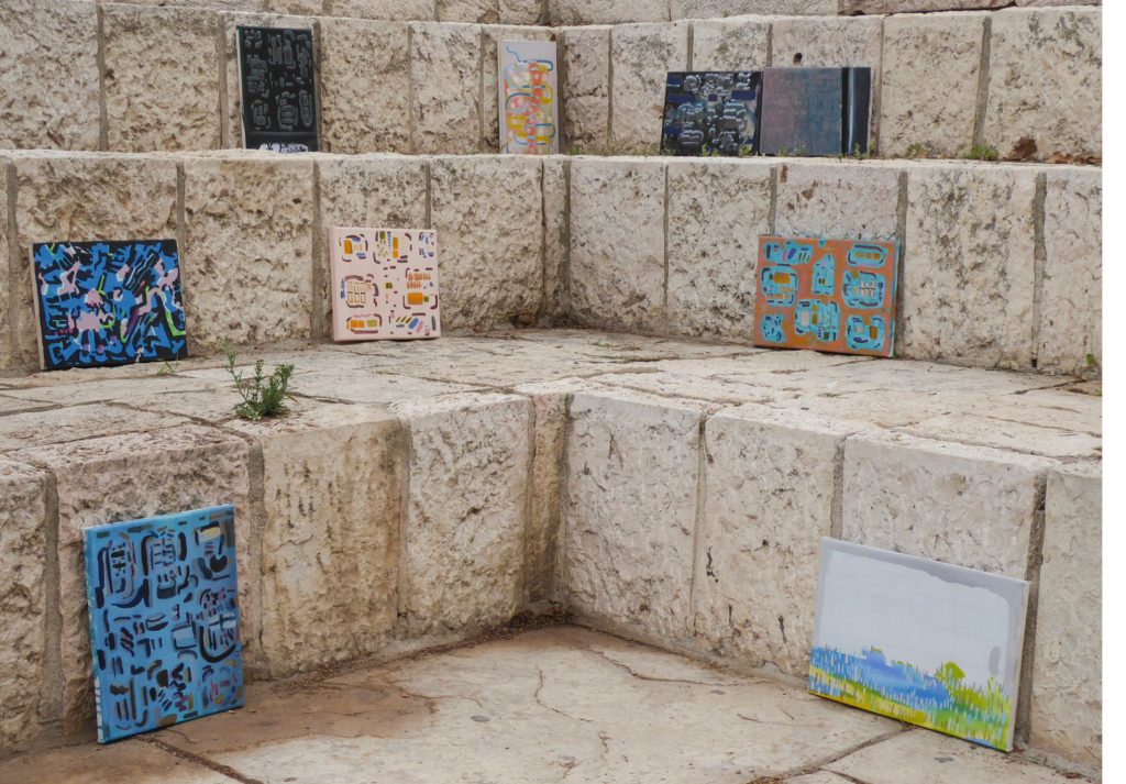 A photograph of three steps of Jerusalem stone. The steps meet at a corner at the center of the photograph with small piles of dried brown leaves along the steps and in a larger pile on the lower left corner. Small green plants grown between the cracks of the limestone. On the top step, four paintings from the series shown in this book lean against the step. On the middle step, three paintings from the series shown in this book lean against the step. On the bottom step, two paintings from the series shown in this book lean against the step.